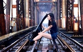 Mädchen sitzen an Bahn spielen Gitarre, Brücke