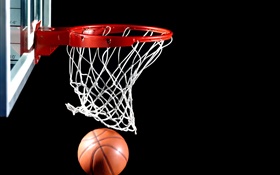 Basketball in den Korb, schwarzer Hintergrund