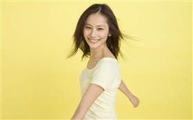 Happy Asian Mädchen, gelber Hintergrund