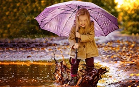 Süßes kleines Mädchen, spiele Wasser, Regenschirm